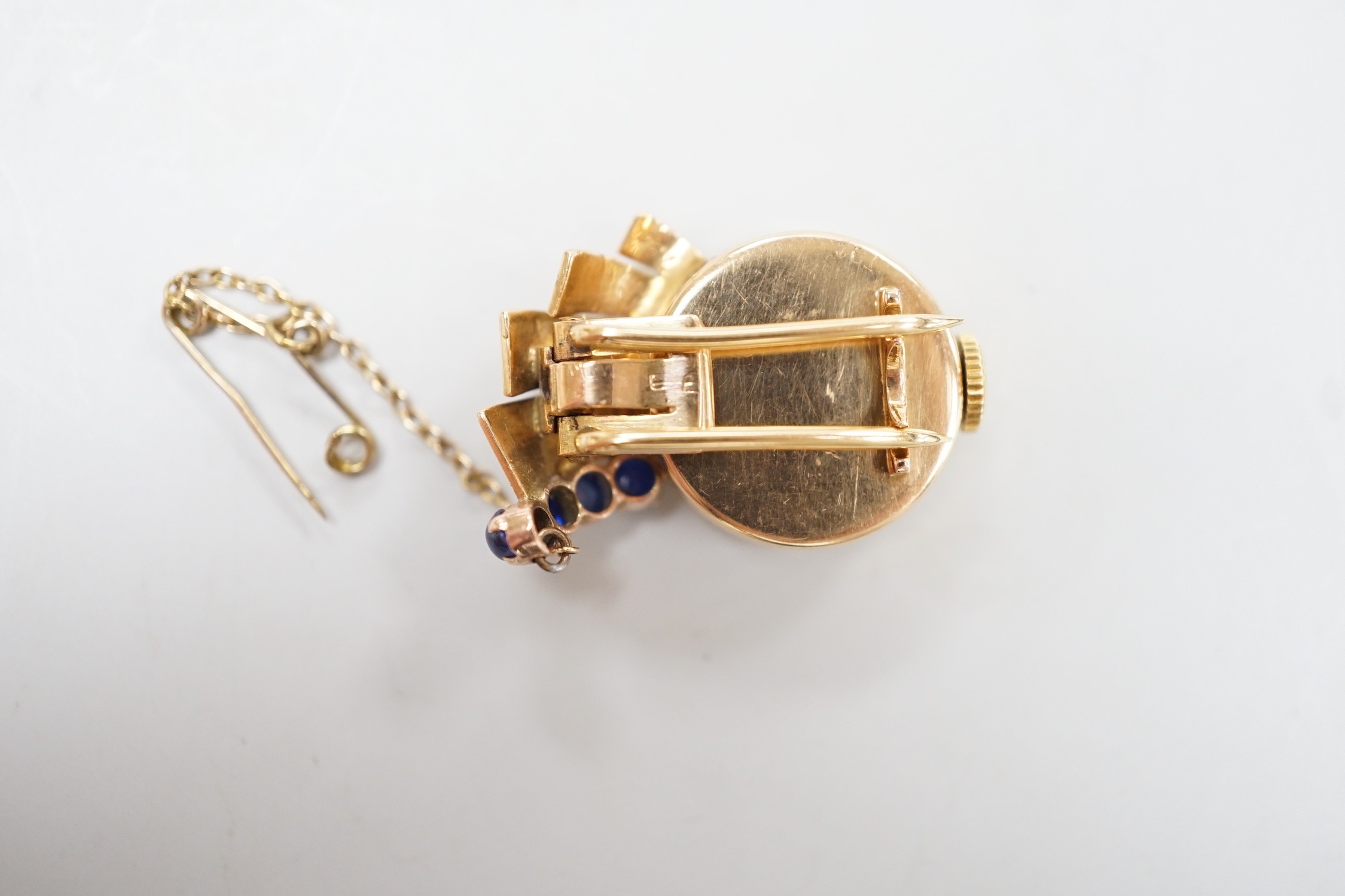 A lady's 1930's/1940's yellow metal and blue cabochon set lapel clip watch, 25mm, gross weight 9.5 grams, with a Richard Ogden gilt tooled leather box.